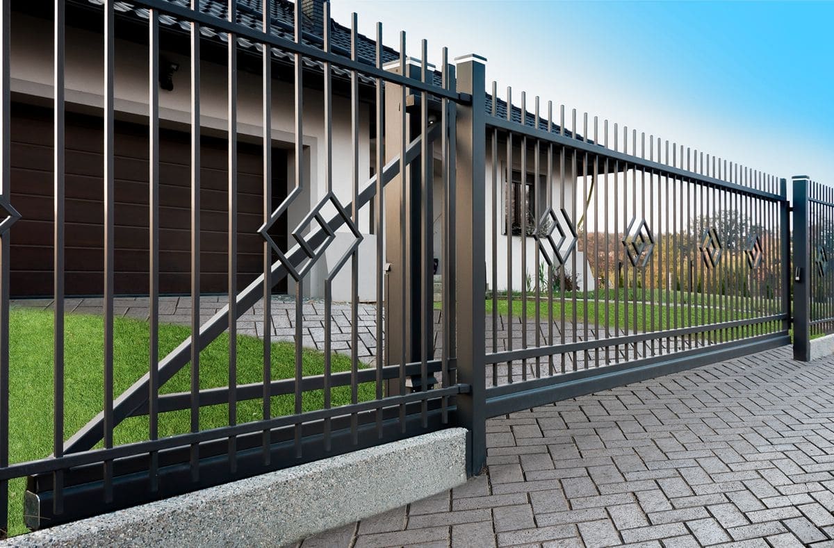 Zwart sierhekwerk en poort bij een moderne woning en groene tuin
